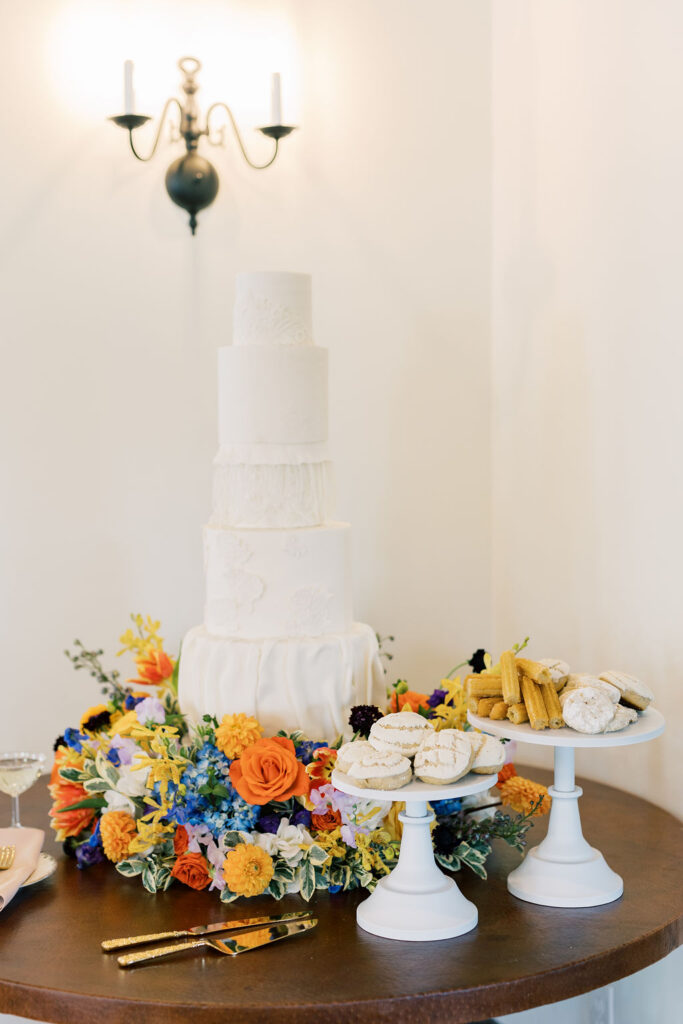 Five-tiered wedding cake surrounded by a colorful flower garden meadow at the base, designed by Kendra’s Events.