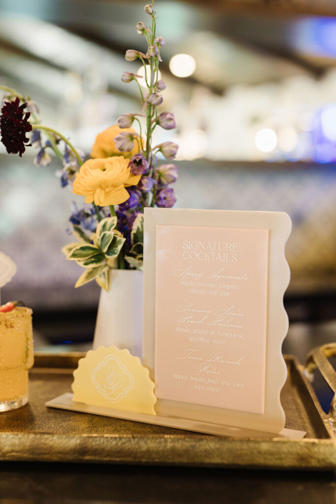 Bud vase centerpiece featuring vibrant flowers, paired with a signature cocktail menu, flowers designed by Kendra’s Events.